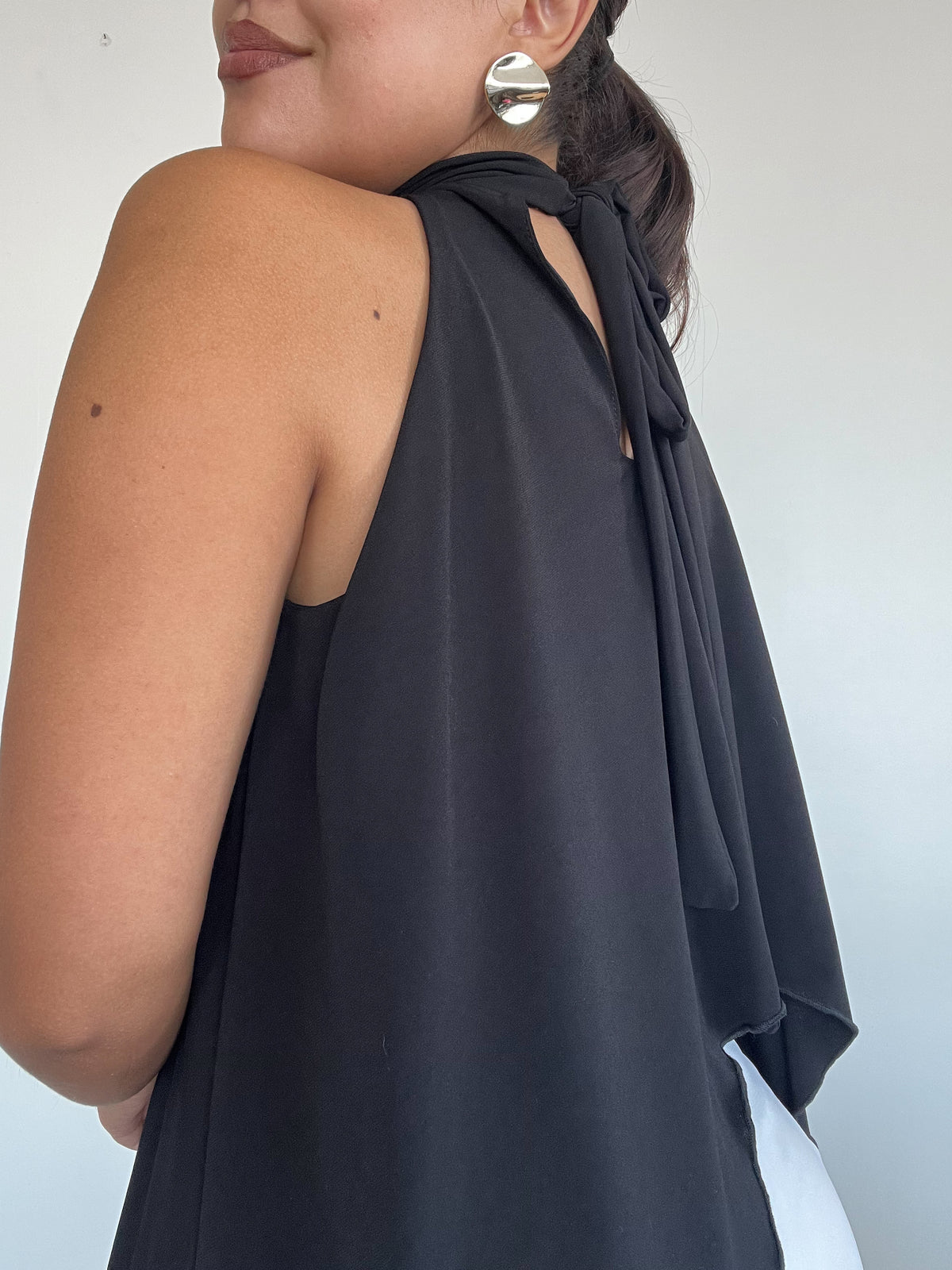 Top polera halter negro estilo capa con amarras, diseño fluido y corte simétrico para mujer