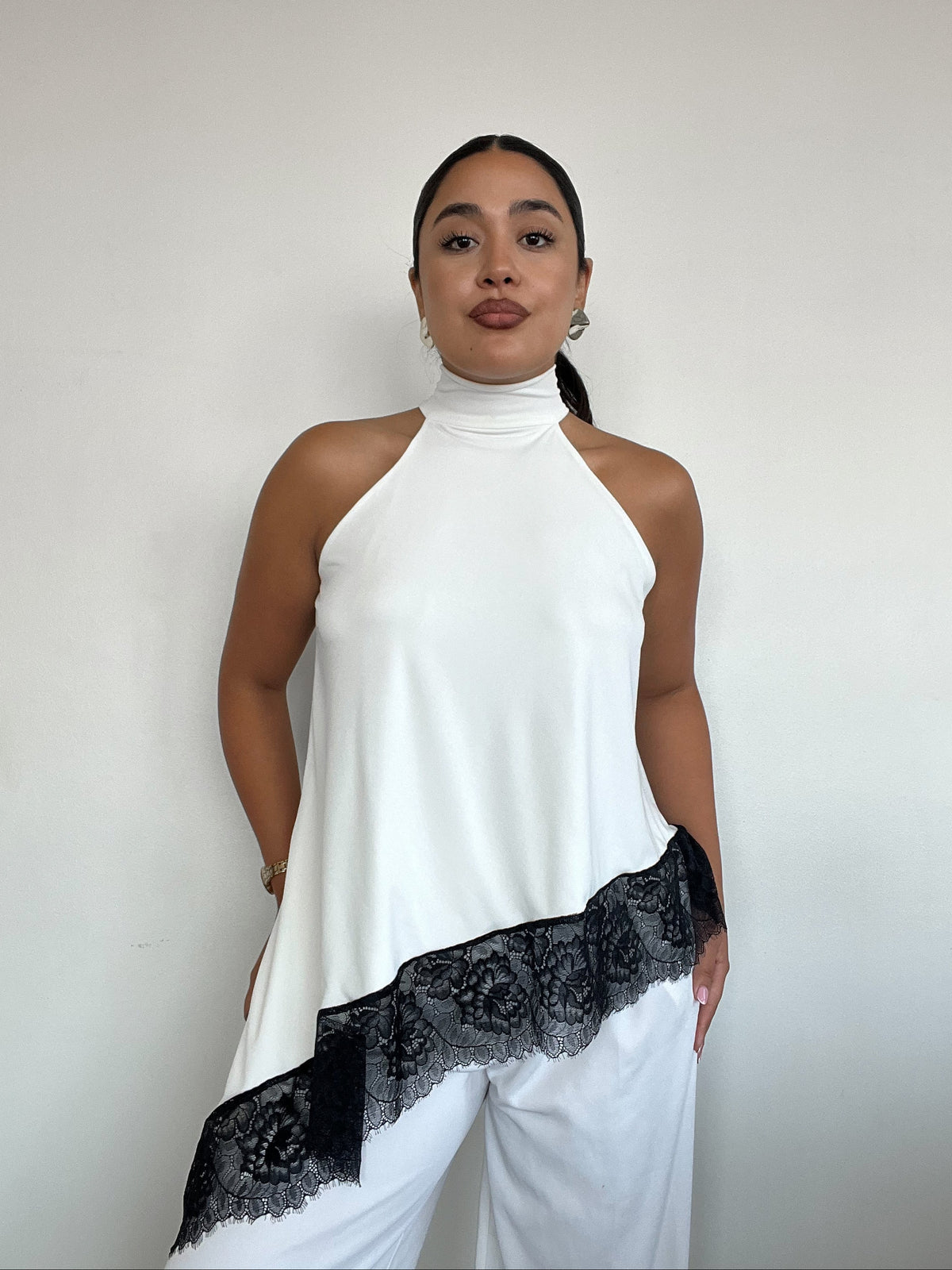 Top polera blanco halter asimétrico con detalle de encaje negro y amarras, diseño elegante para mujer