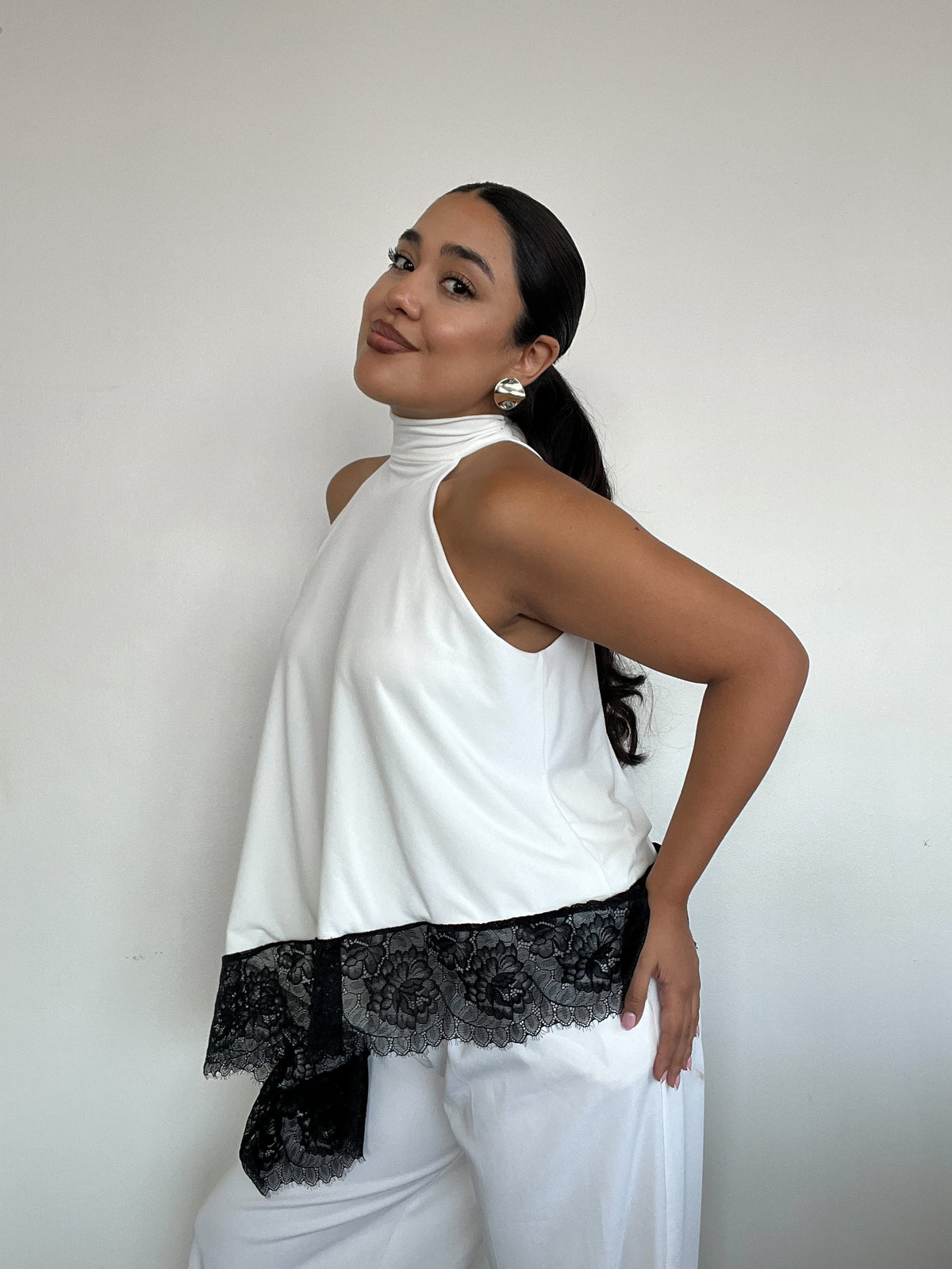 Top polera blanco halter asimétrico con detalle de encaje negro y amarras, diseño elegante para mujer