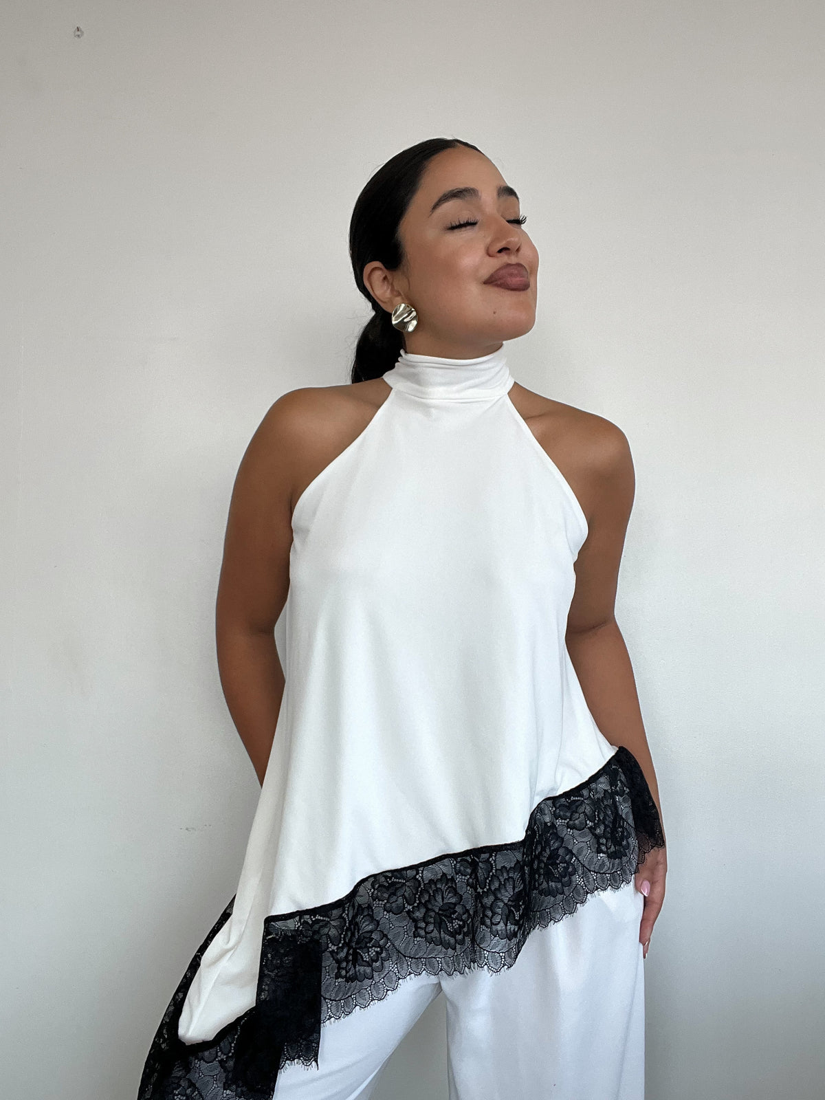 Top polera blanco halter asimétrico con detalle de encaje negro y amarras, diseño elegante para mujer