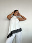 Top polera blanco halter asimétrico con detalle de encaje negro y amarras, diseño elegante para mujer
