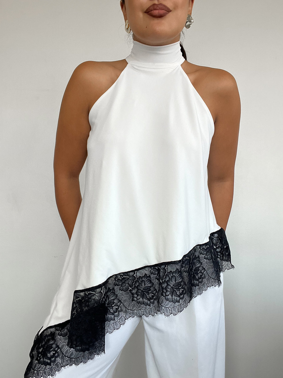 Top polera blanco halter asimétrico con detalle de encaje negro y amarras, diseño elegante para mujer
